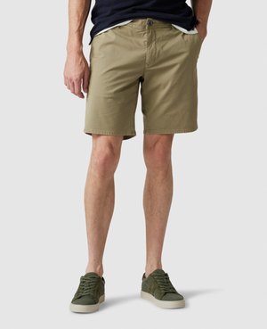 A person is standing against a plain background wearing a navy blue shirt, Rodd & Gunn The Peaks Custom Shorts, and olive green sneakers with white soles. Only the lower half of their body is visible.