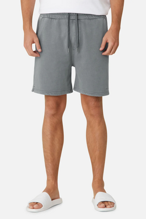 A person is wearing Industrie The Del Sur Track Shorts in gray, which have an adjustable drawstring and elastic waist for a casual oversized fit, along with a white T-shirt and white slide sandals against a plain white background.