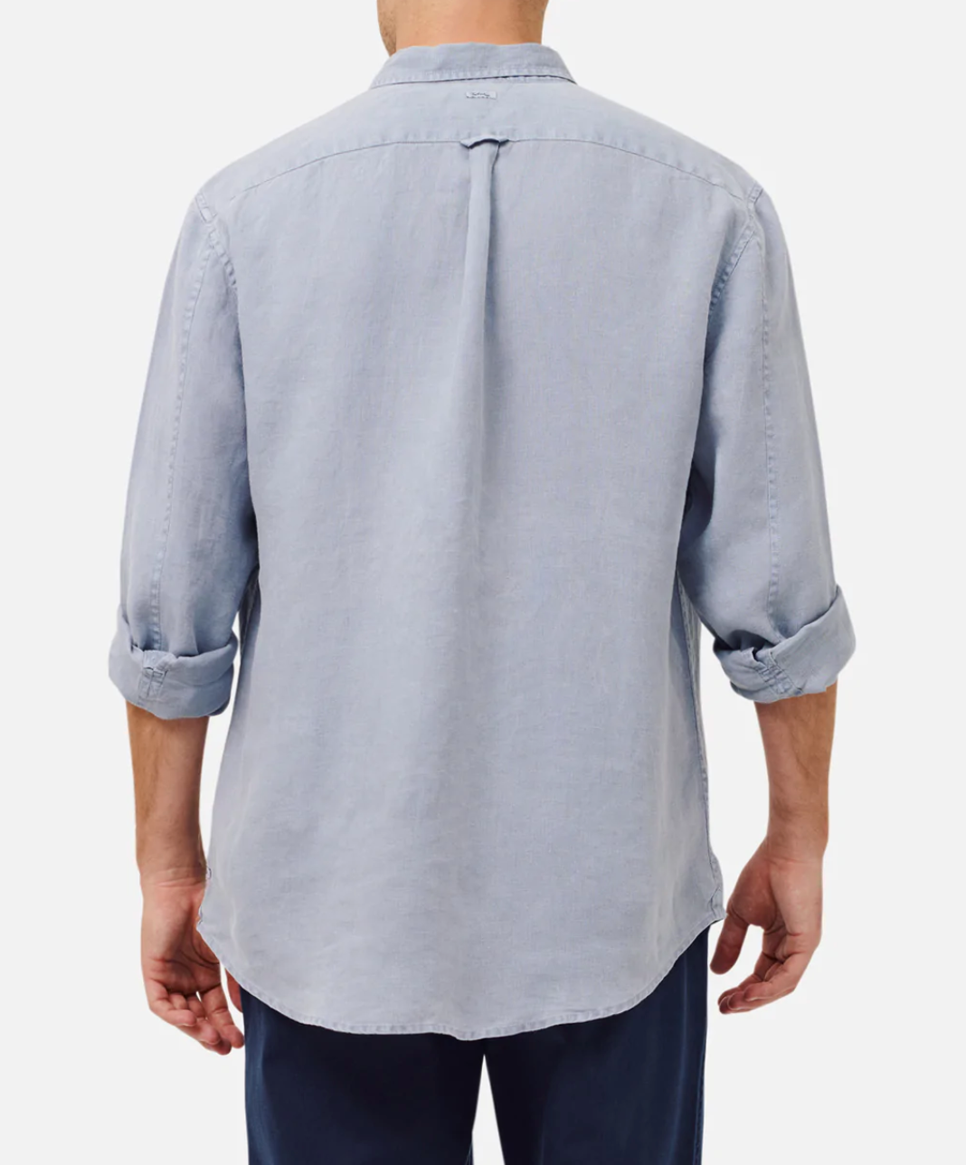 A person is seen from the back wearing an Industrie The Tennyson Linen Shirt in relaxed fit, light blue, and 100% linen. The sleeves are rolled up, paired with dark pants against a plain white background.