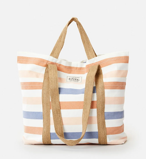 The Rip Curl Organic 29L Beach Tote is a striped canvas bag made from organic cotton, featuring horizontal stripes in orange, blue, and cream. It has dual brown fabric handles and a small rectangular label on the front, standing out against its plain white background.