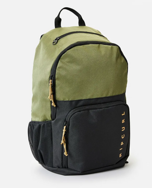 The Rip Curl Evo 24L Overland Backpack in green and black features a gold-lettered front pocket, is made from recycled polyester, includes a laptop section, two beige pull string zippers, and a sturdy black top handle.