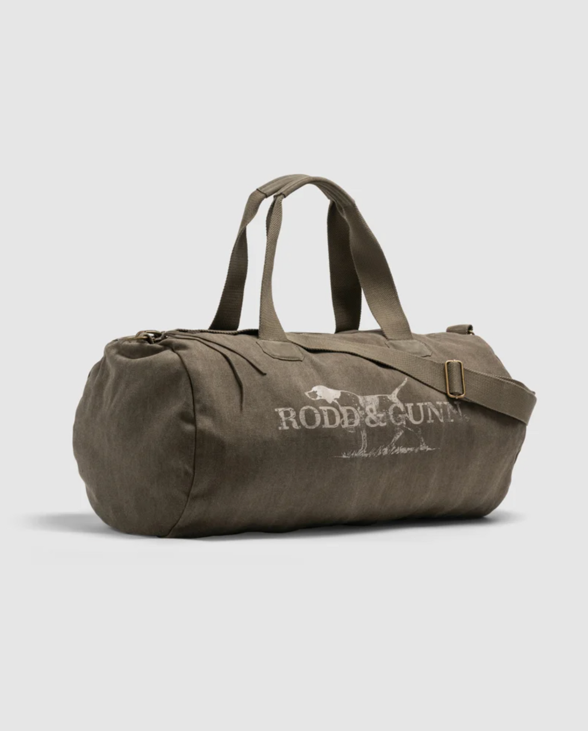 The Rodd & Gunn Double Barrel Duffle Bag is an olive-green cylindrical carryall made from durable cotton canvas, featuring dual handles, a shoulder strap, and the iconic logo with a dog graphic and white text on its side.