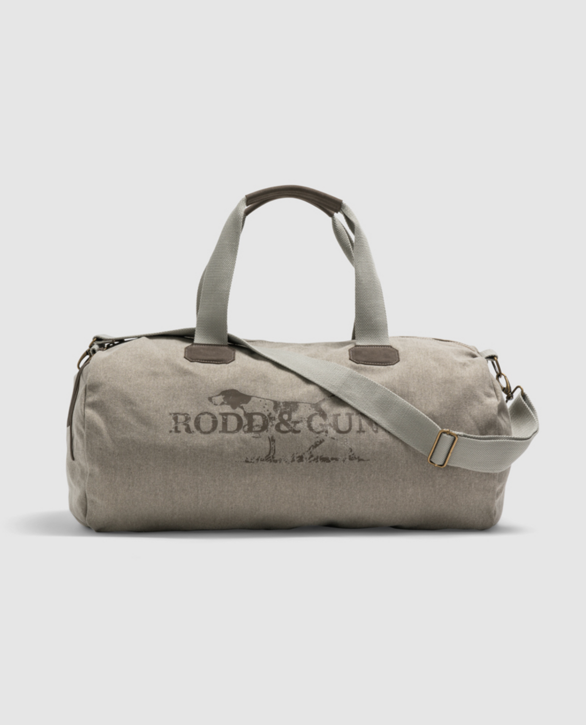 The beige Rodd & Gunn Double Barrel Duffle Bag features a dark logo, dual handles, and a detachable shoulder strap. It includes metal zippers and buckles, stands upright against a light gray background, and is ideal for travel.