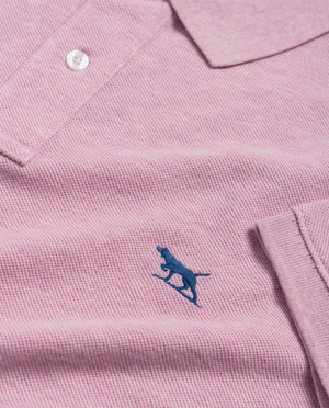 The Rodd & Gunn The Gunn Polo is a close-up of a light pink modern-fit polo shirt with a collar and one visible white button, crafted from premium Australian cotton. It features a small blue embroidered silhouette of a running cheetah on the fabric.