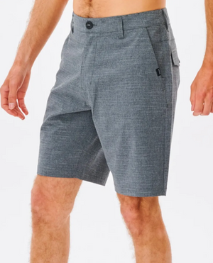 A person is wearing Rip Curl Boardwalk Epic Mix Short in gray with a subtle checkered pattern. These knee-length shorts feature front and back pockets, a buttoned waistband, and are made from quick-dry, stretch recycled polyester against a white background.