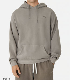 A person is wearing the Industrie The Del Sur Hoodie in gray with an embroidered chest logo and matching sweatpants. This comfy oversized hoodie has a drawstring hood and front pocket. The crisp white backdrop enhances its casual appeal.