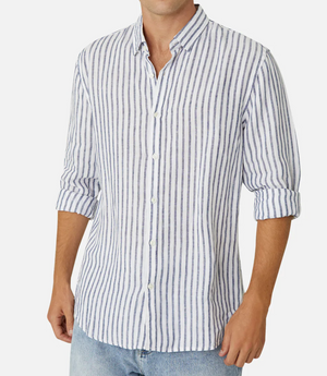 A person is wearing the Industrie The Feliz Shirt, a classic fit, 100% linen shirt in white with vertical blue stripes, rolled-up sleeves, a collar, and buttons down the front. They pair it with light blue jeans against a plain white background.