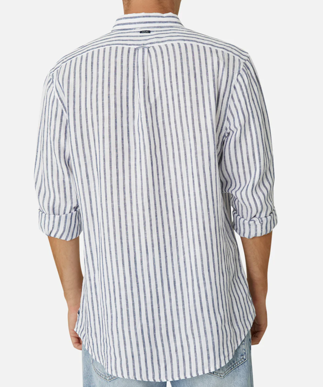 A person is seen from behind wearing Industrie The Feliz Shirt, a classic fit, long-sleeved white shirt with thin vertical blue stripes made of 100% linen. Sleeves are rolled to the elbows and paired with light blue jeans against a plain white backdrop.