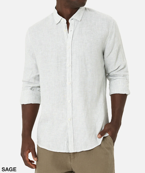A person is wearing the Industrie The Rochecroft Shirt, a light, long-sleeved button-up with the sleeves partially rolled up. This relaxed-fit shirt is made from 100% linen and features a "Sage" label on the bottom left corner. It's paired with light brown pants against a plain white background.
