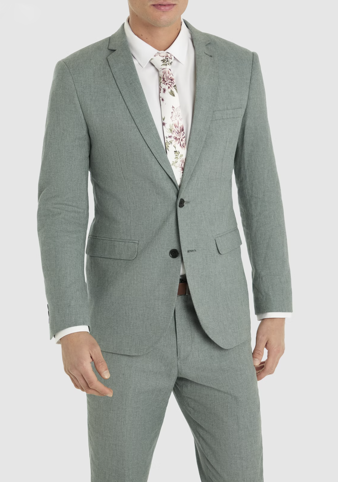 Connor stands against a plain white background, wearing the Connor Scarborough Slim Blazer in light gray, paired with a white dress shirt and a floral-patterned tie.