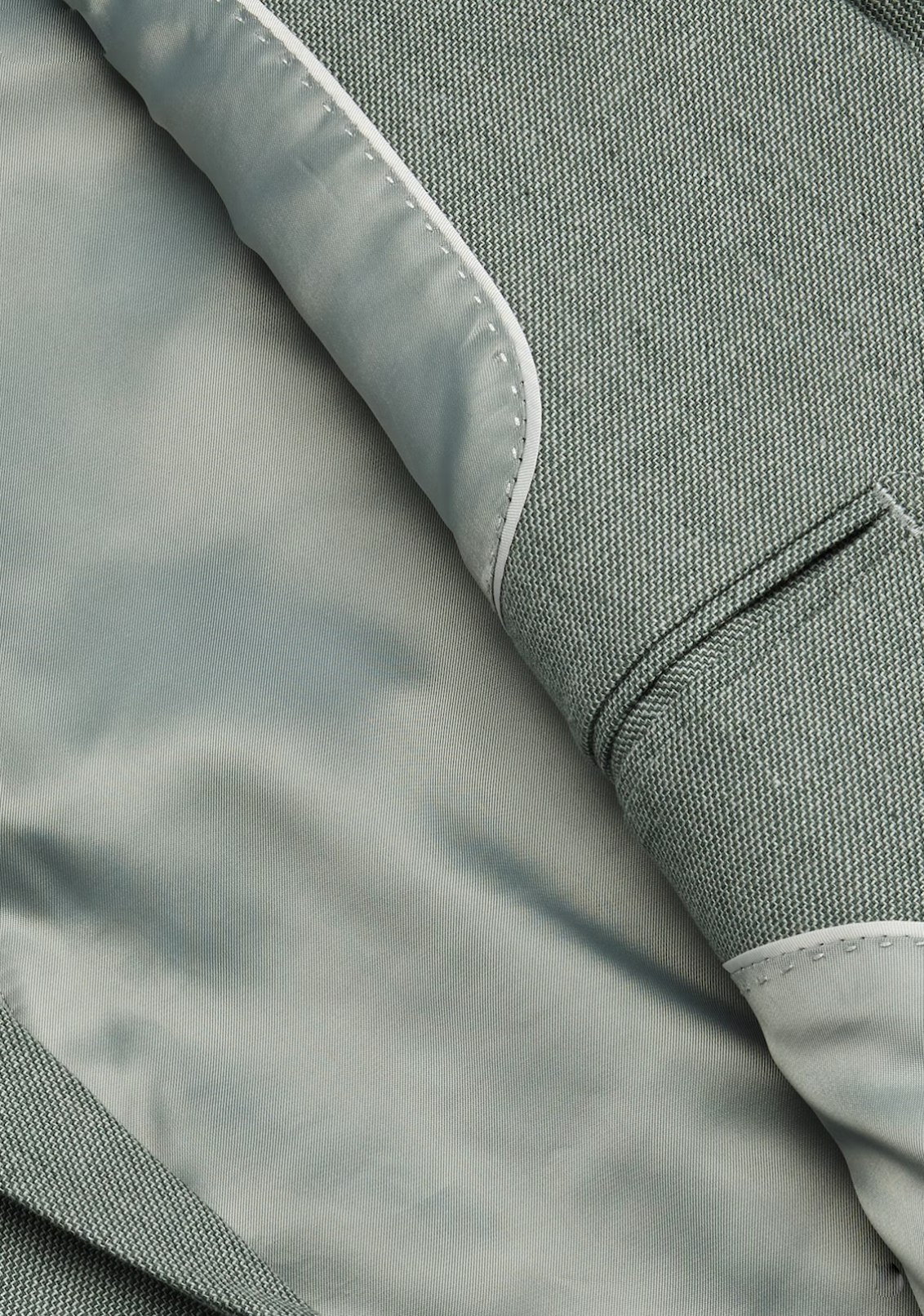 Close-up of the Connor Scarborough Slim Blazer interior, featuring smooth gray lining, a pocket with stitching detail, and a lapel with contrasting textured design.