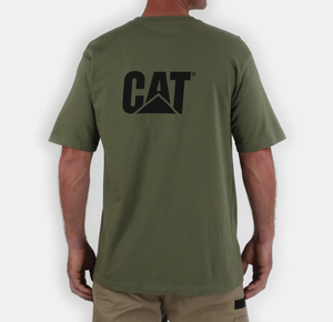 A person stands with their back to the camera wearing a CAT Trademark Tee, made of 100% cotton in green, featuring bold black "CAT" lettering on the back. They pair it perfectly with beige shorts against a plain white background.