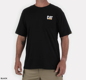 A person wearing a comfortable CAT Trademark Tee, which is black and features a small white and yellow CAT logo on the left chest. The individual has short sleeves and is also dressed in khaki pants, ideal for job site safety. The background is white.