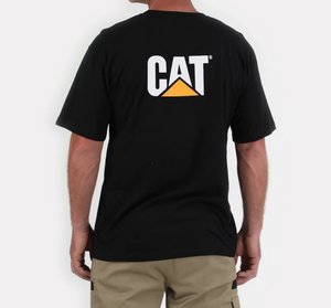 A person wearing the CAT Trademark Tee, featuring 100% cotton and a unique "CAT" logo with an orange triangle, is facing away. They are paired with khaki shorts against a plain white background.