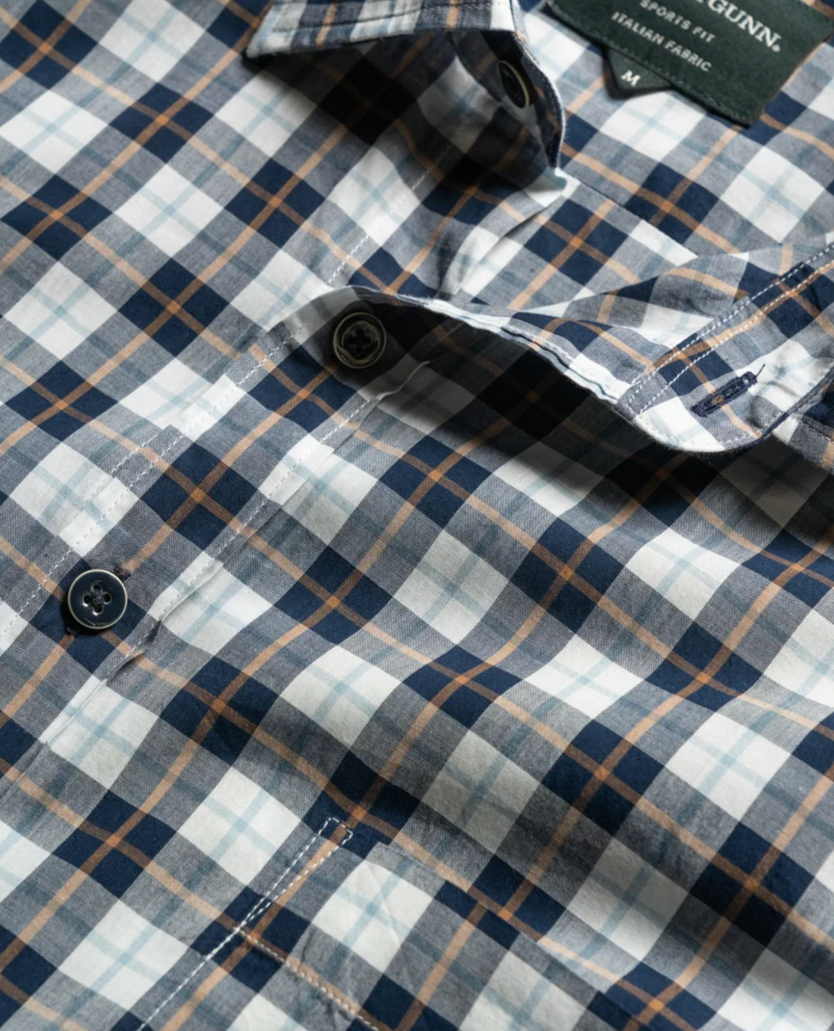 Close-up of the Rodd & Gunn Mount Albert Sports Fit Shirt in a navy, white, and brown plaid pattern. Made from 100% cotton, this slim fit shirt includes a button-down front and a small label near the collar.
