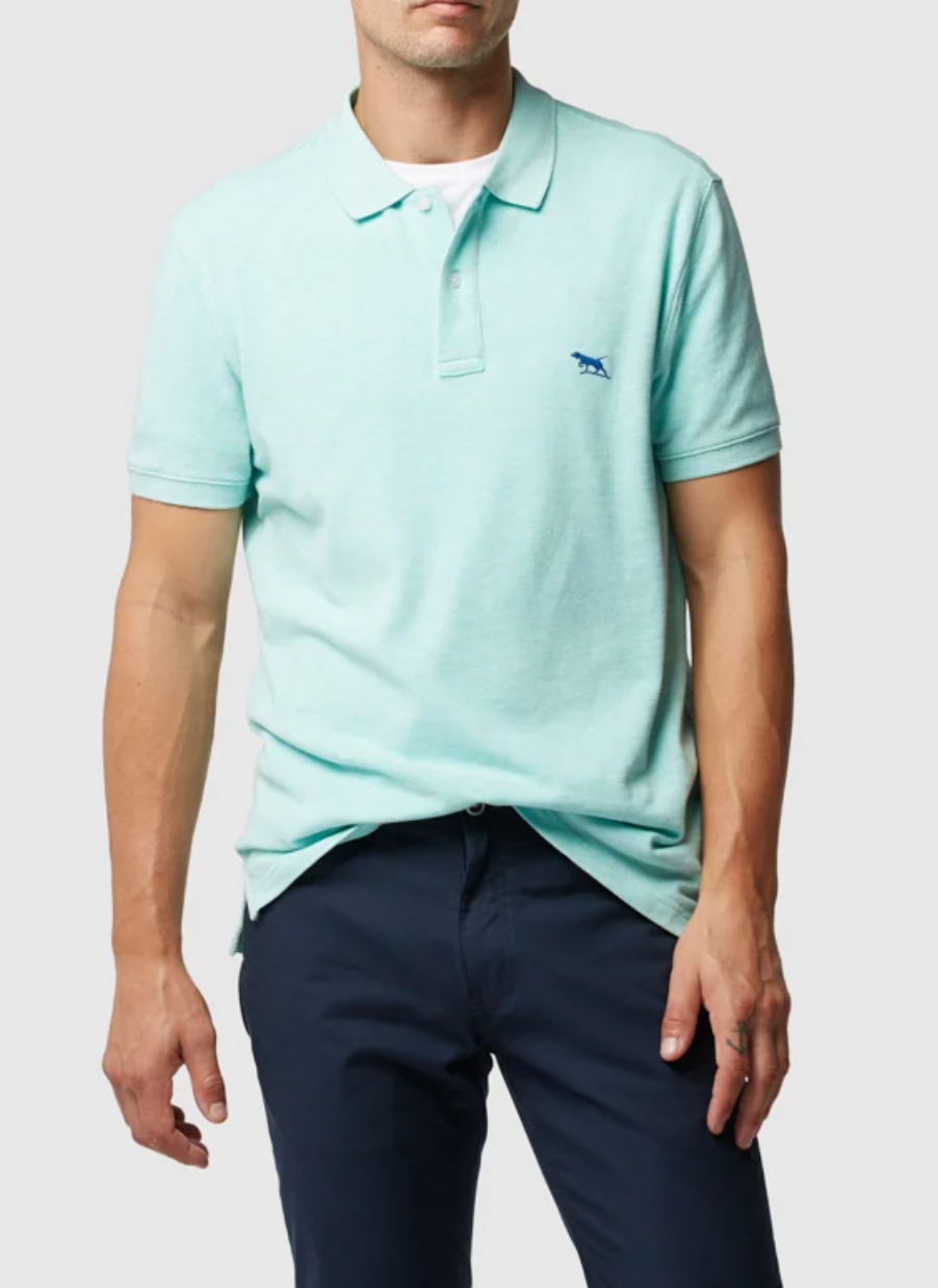 Sporting the Rodd & Gunn The Gunn Polo in a modern-fit light teal with an embroidered animal logo on premium Australian Cotton, the man pairs it with dark navy pants for a sleek look against a plain white background.