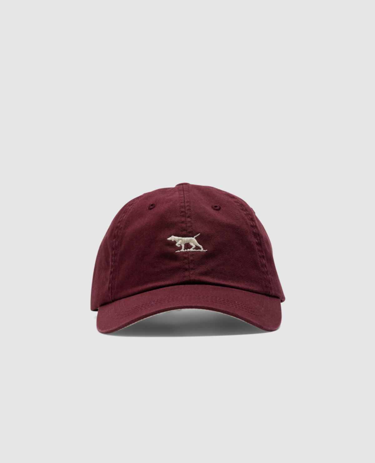 The Rodd & Gunn Gunn Cap, made from durable burgundy cotton twill, displays a small embroidered bear logo on the front with a plain gray backdrop.
