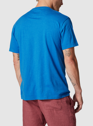 A person in a blue Rodd & Gunn The Gunn T-Shirt, made from premium Australian Cotton and designed in a sports fit, pairs it with red shorts while facing away from the camera. Their T-shirt beautifully complements their arm tattoos, including a butterfly on the left forearm.
