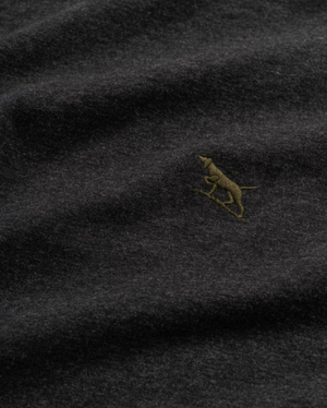 Close-up of Rodd & Gunn The Gunn T-Shirt, a dark gray fabric tee featuring a small embroidered yellowish-brown dog figure. Made from soft Australian cotton, it boasts a gentle and slightly textured feel.