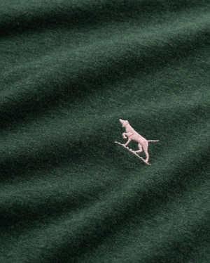 The Rodd & Gunn The Gunn T-Shirt, made from Australian Cotton, showcases a dark green color with a small pink dog embroidered over a diagonal line. Its sports fit offers both comfort and style for daily wear.