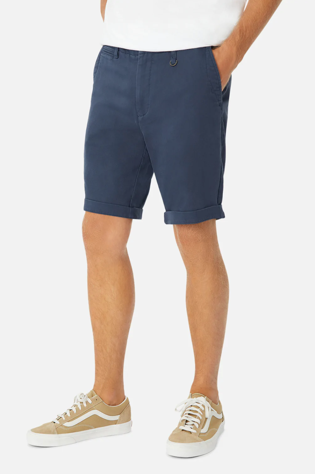 Someone is wearing relaxed-fit, navy blue Industrie The Rinse Drifter Shorts made from cotton elastane, paired with a crisp white shirt and tan sneakers featuring white laces and soles. The plain white backdrop emphasizes the casual fashion style of this effortlessly chic look.