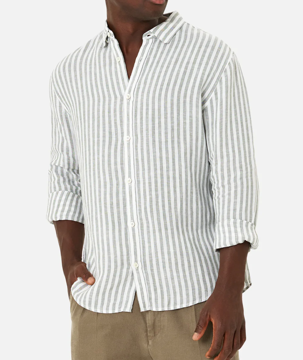 A person wears the Industrie The Bayshore Linen Shirt, a comfortable 100% linen light gray and white vertically striped button-down with rolled-up sleeves, paired with khaki pants against a plain white background, hands in pockets.