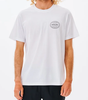 A person wears the Rip Curl Vaporcool Oval Tee, a plain white short-sleeve shirt with a small circular logo on the left chest and quick-dry, moisture-wicking fabric, paired with black shorts against a plain white background.