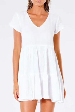 Someone wears a Rip Curl Premium Surf Dress, a white short-sleeved V-neck design, against a white background. This dress boasts a soft textured fabric with a loose, flowing skirt, ideal for casual occasions.