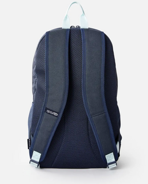 The Rip Curl Heat Wave Ozone 30L Backpack in navy blue, with light blue handles and straps, is shown from the back. It has two adjustable straps, breathable mesh fabric, and is crafted from recycled polyester with a visible logo on the strap for an eco-friendly and stylish design.
