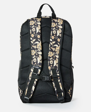 The Rip Curl Overtime 30L Backpack showcases its floral-patterned shoulder straps, ventilated mesh back panel, and adjustable straps with a support buckle. Made from recycled polyester, it is compatible with 15" laptops.