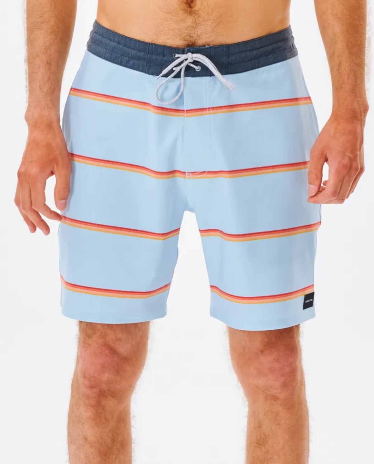 A person dons Rip Curl Monarch Layday boardshorts in light blue with red and orange horizontal stripes and a dark waistline. These quick-drying shorts include a drawstring and a small black label on the lower left, set against a plain white background.