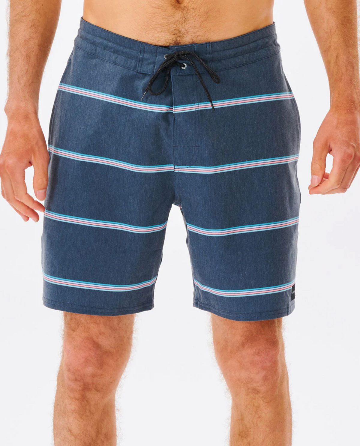 A person in Rip Curl Monarch Layday boardshorts, featuring quick-drying blue fabric with horizontal white and pink stripes, just above the knees. The backdrop is plain white, ideal for a splash or two.