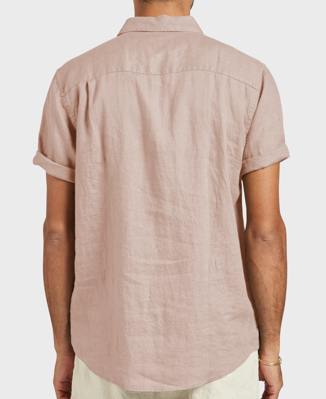 A person is shown from the back wearing the Academy Brand Hampton Linen Short Sleeve Shirt in light pink. It's a regular fit with a point collar, rolled-up short sleeves, and worn untucked for a casual look against a plain white background.