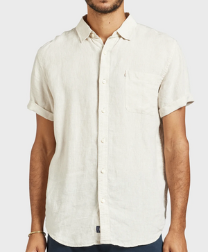 A man wears the Academy Brand Hampton Linen Short Sleeve Shirt in regular fit, off-white, featuring a left chest pocket. He stands against a plain light background with his head out of frame.