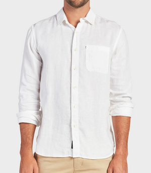 Someone wearing the Academy Brand Hampton Linen Shirt, a regular fit, long-sleeved white linen shirt with a single pocket and partially rolled-up sleeves, paired with beige pants against a plain light gray background.