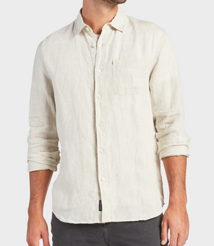 A man wears a regular-fit, beige Academy Brand Hampton Linen Shirt with a collar and chest pocket, sleeves slightly rolled up, paired with dark pants against a plain white background.