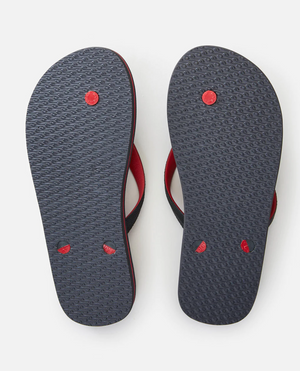 The image displays a pair of Rip Curl MC 2 Tone Thongs in black and red, viewed from the bottom on a plain white background. They feature textured soles for grip and thermo rubber compound straps for comfort.