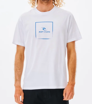 A person wears a casual white Rip Curl Corp Icon Tee with short sleeves and a blue square chest logo, made from 100% cotton, paired with dark shorts. The person's head is partially out of frame.
