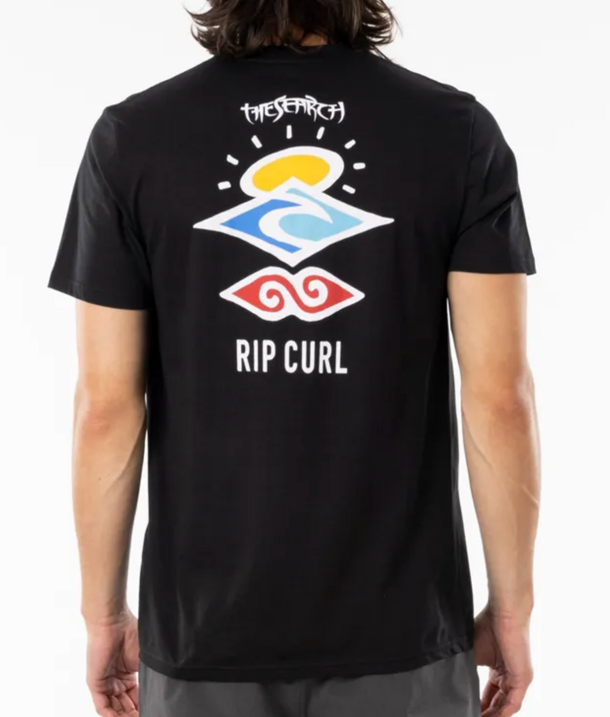 A person wearing the Rip Curl Search Icon Tee, crafted from organic cotton, featuring colorful abstract symbols and "The Search" and "Rip Curl" on the back, with sun, wave, and swirl icons reflecting nature and exploration themes.