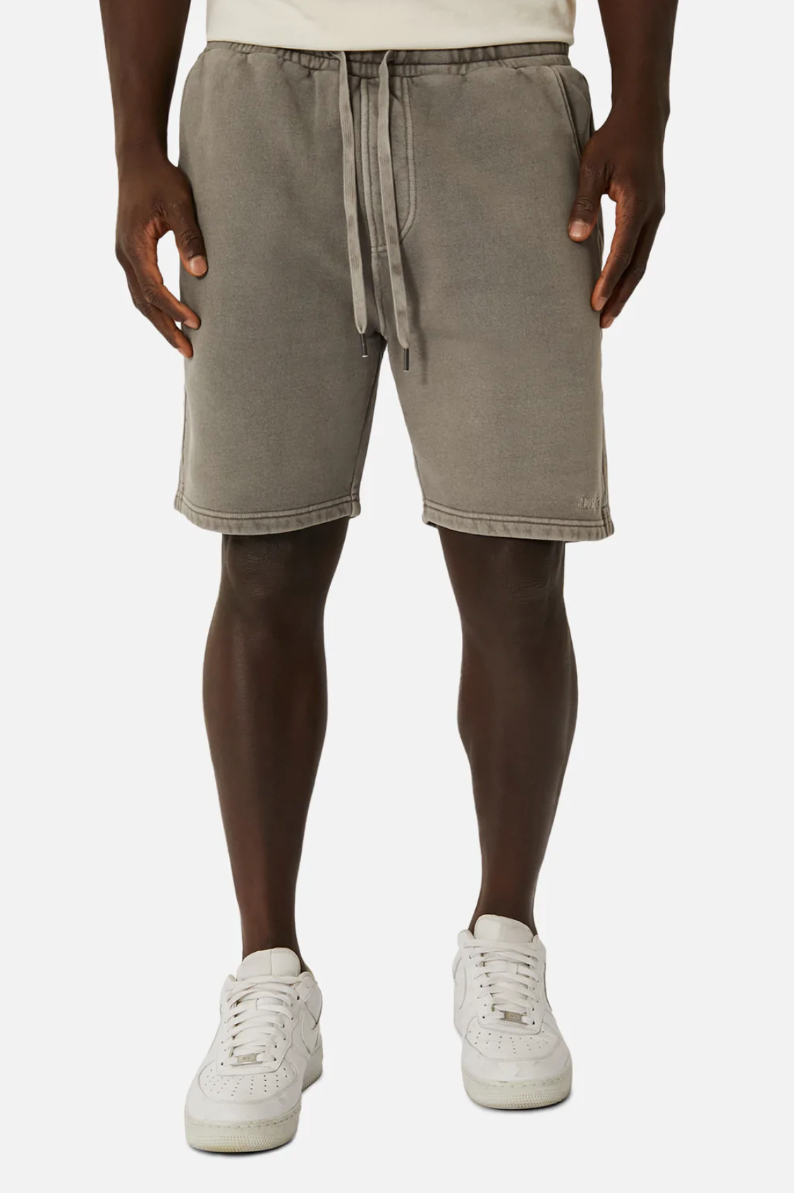 Wearing Industrie The Del Sur Track Short in gray with an elastic waist and oversized fit, and white sneakers paired with low-cut socks, a person stands against a plain background. The look is simple and sporty.