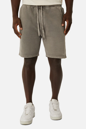 Wearing Industrie The Del Sur Track Short in gray with an elastic waist and oversized fit, and white sneakers paired with low-cut socks, a person stands against a plain background. The look is simple and sporty.