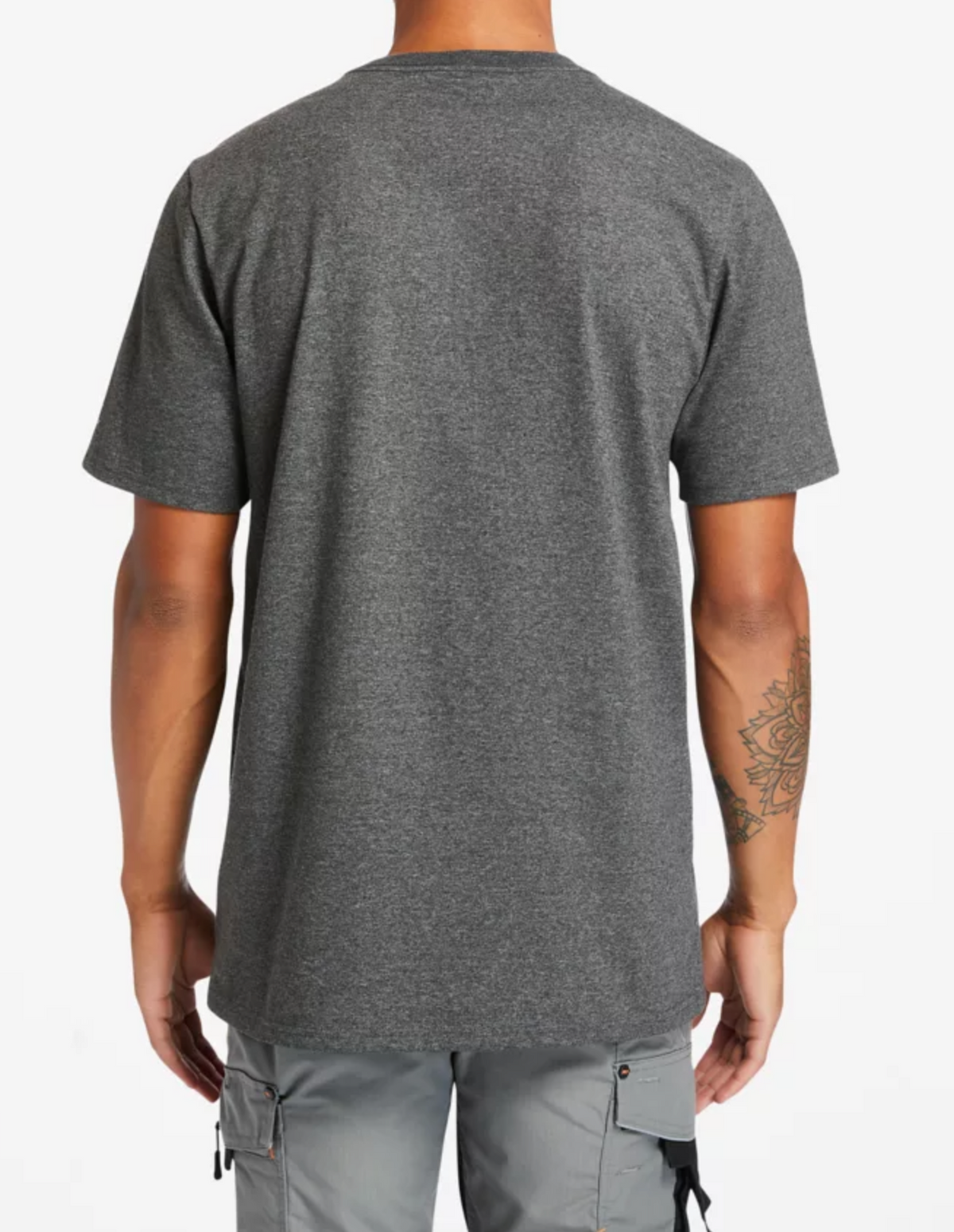 A person is shown from behind in a Timberland Pro Base Plate Logo Tee, an original fit plain gray T-shirt, paired with light gray cargo pants. A tattoo peeks from beneath the sleeve, hinting at stories untold.