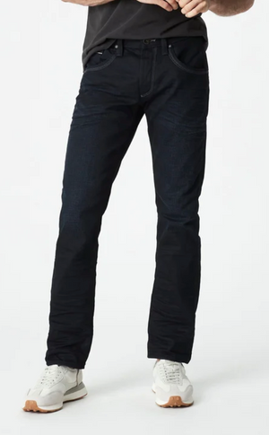 Wearing Mavi Marcus Slim Straight Jeans, a black shirt, and white sneakers, a person stands against a plain white background with only the lower half of their body visible.