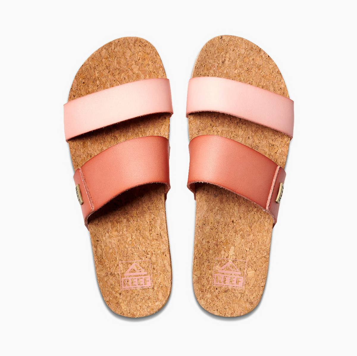 The REEF Cushion Vista Duo sandals feature two-tone light pink and reddish-brown straps on a white backdrop. Natural cork-textured footbeds with "REEF" at the heel are complemented by a cushion bounce midsole for enhanced comfort.