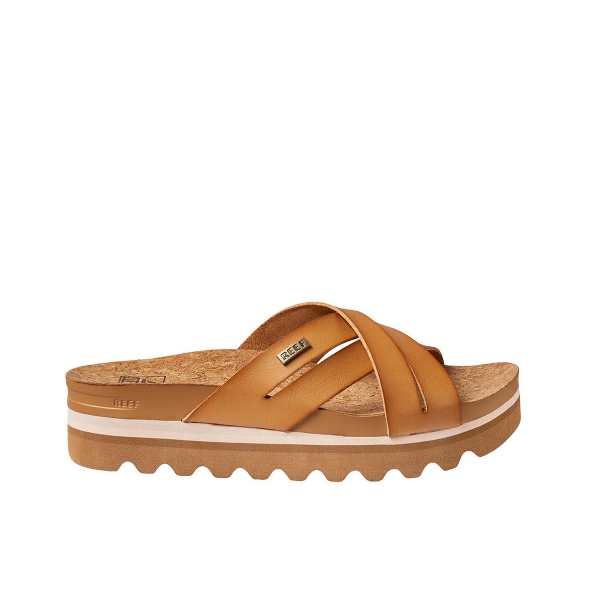 The REEF Cushion Bloom Hi sandal in tan showcases crisscross leather straps, a cushion bounce midsole, a cork footbed, and a thick beige and tan striped platform sole with wavy tread. It includes a small metallic brand tag on one strap.