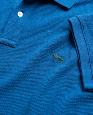 Close-up of the Rodd & Gunn The Gunn Polo in blue, made with soft Australian cotton. It boasts a dog logo embroidered on the chest, folded short sleeves, and white collar buttons for a modern fit that combines comfort and timeless style.