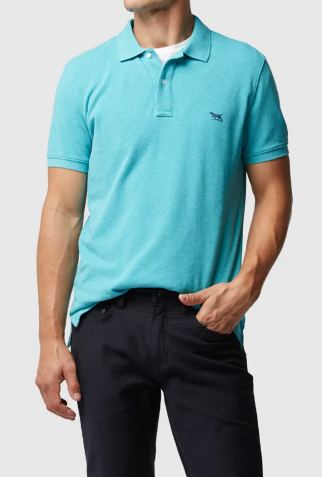 A person in a turquoise Rodd & Gunn The Gunn Polo, featuring a small left-chest logo and made of soft Australian Cotton, paired with black pants, stands against a plain background. The shirt is front-tucked as their left hand casually rests in their pocket.