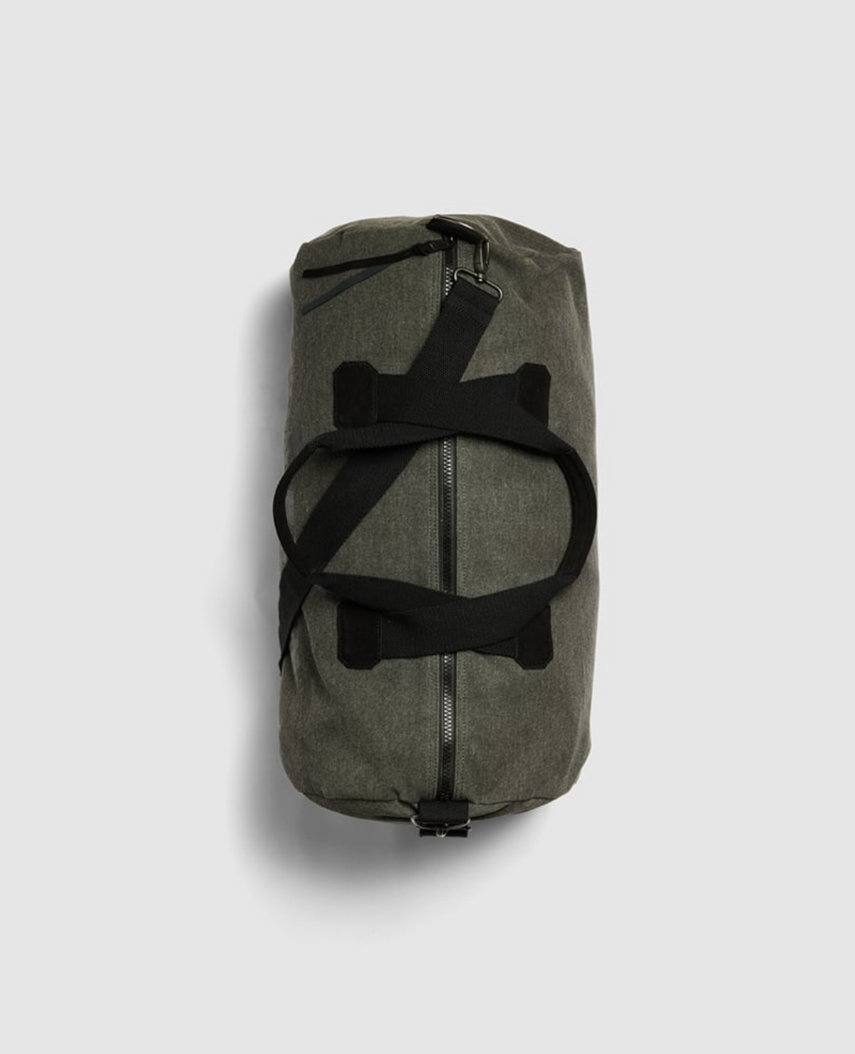 The dark green Rodd & Gunn Double Barrel Duffle Bag, made from cotton canvas, is set against a gray background. It features black straps crossing over the top and a zipper running along its cylindrical length.