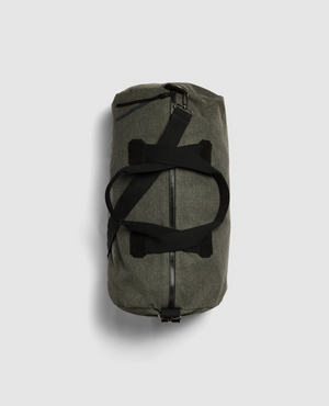 The dark green Rodd & Gunn Double Barrel Duffle Bag, made from cotton canvas, is set against a gray background. It features black straps crossing over the top and a zipper running along its cylindrical length.