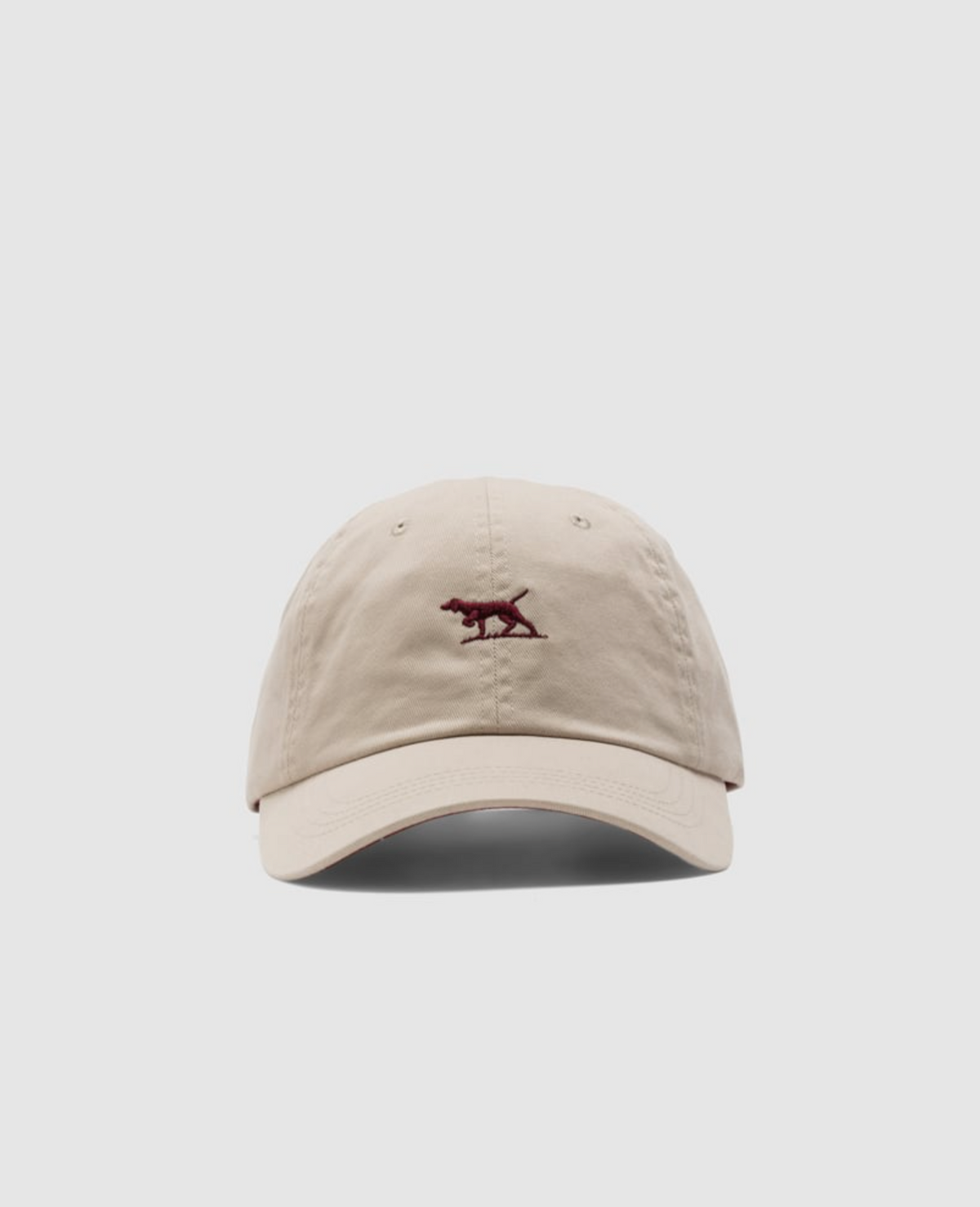 The Rodd & Gunn Gunn Cap, crafted from heavy-duty beige cotton twill, showcases a maroon embroidered dog logo on its front. The cap features a curved brim and is presented against a plain white backdrop.